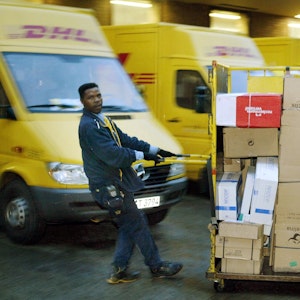 Ein Zusteller der DHL zieht in Dortmund einen Paketwagen zu seinem Fahrzeug (Archivfoto vom 21.10.2003).
