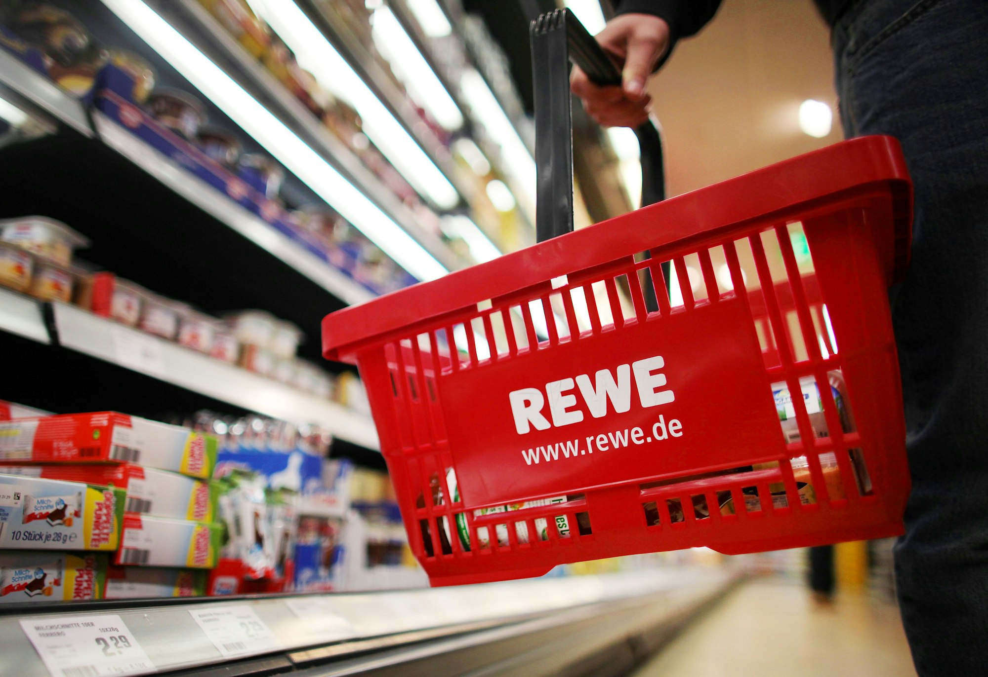 Ein Kunde geht am 13. Februar 2012 in Köln (Nordrhein-Westfalen) in einem Rewe-Supermarkt mit einem Einkaufskorb am Kühlregal entlang.