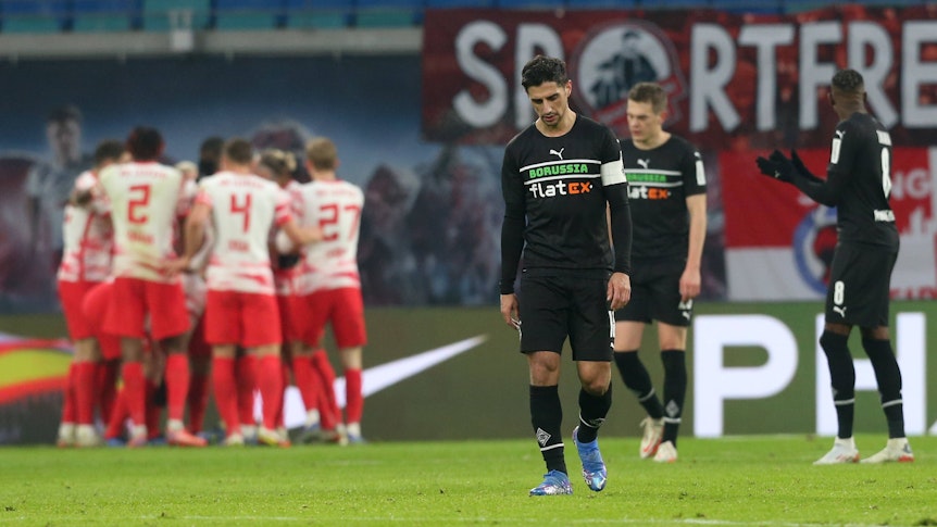 Enttäuschung bei den Gladbach-Profis um Kapitän Lars Stindl, im Hintergrund jubeln die die Leipziger über einen Treffer im Bundesliga-Duell am 11. Dezember 2021 in der RB-Arena. Lars Stindl schaut niedergeschlagen auf den Boden.