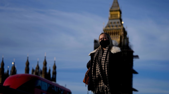 Eine Frau mit Mund-Nasen-Schutz überquert die Westminster Bridge.