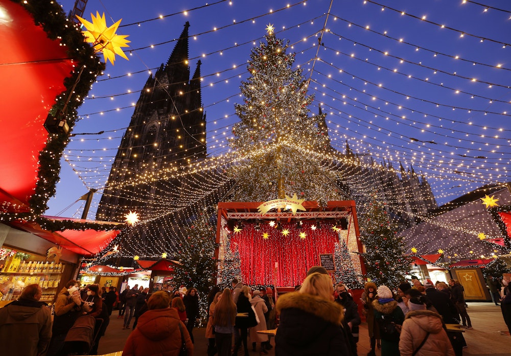 Besucher gehen über den Weihnachtsmarkt auf dem Roncalliplatz am Kölner Dom.