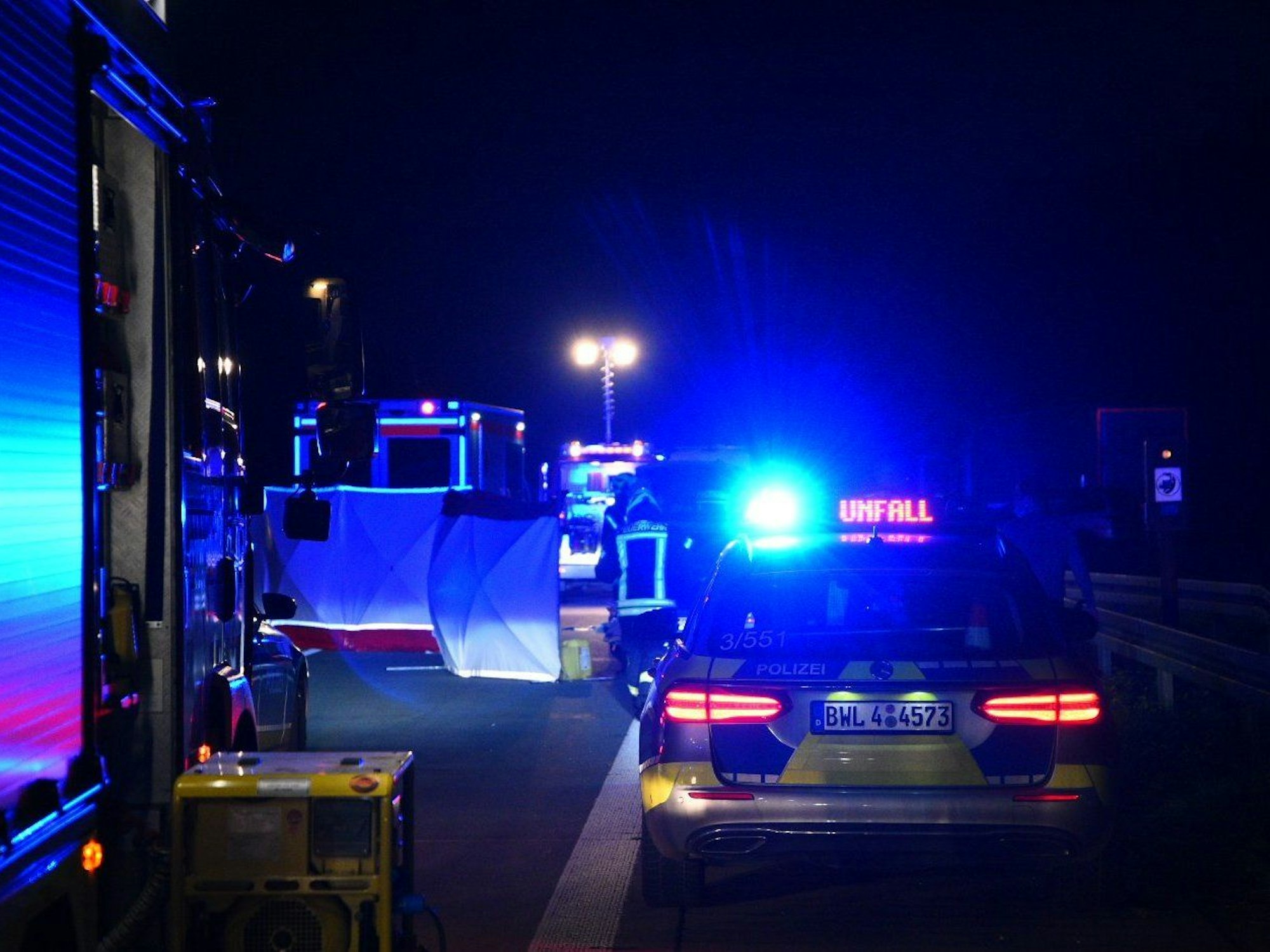 Einsatzfahrzeuge von Polizei und Feuerwehr stehen mit Blaulicht an der Unfallstelle.