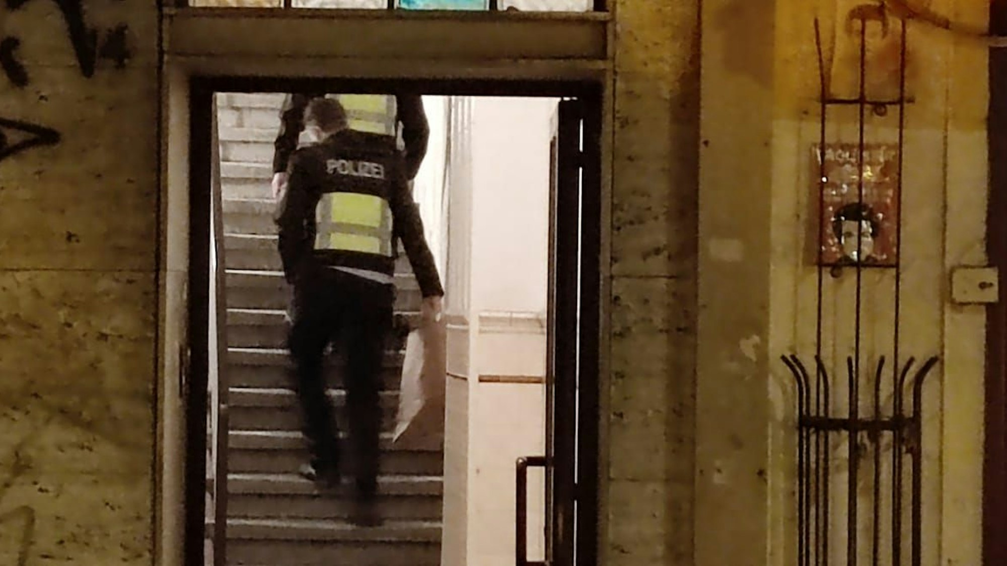 Zwei Polizisten gehen eine Treppe in einem Haus hoch.