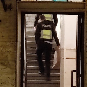 Zwei Polizisten gehen in einem Hausflur die Treppe hoch.