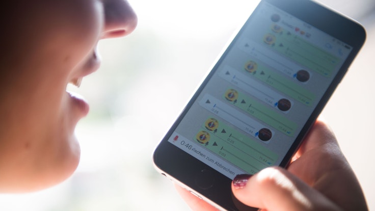 Eine Frau spricht eine Sprachnachricht in ein Smartphone und nutzt dafür den Messangerdienst Whatsapp.