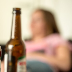 Alkoholsucht ist weiterhin ein großes Problem unserer Gesellschaft. Jetzt erzählt der Ex-Alkoholikerin Nathalie, wie es ihr ergangen ist. Unser Symbolfoto (28. Mai 2016) zeigt eine junge Frau, die hinter leeren Bierflaschen sitzt.