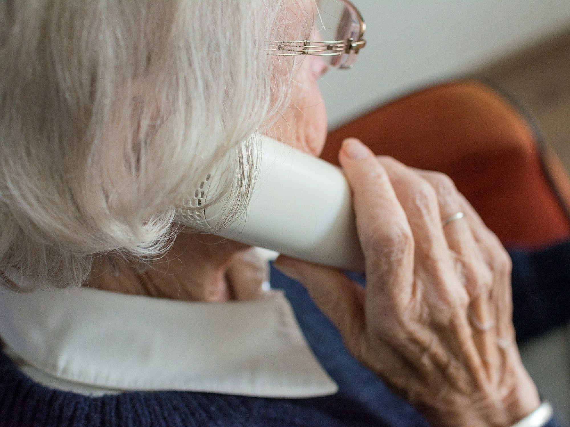 Eine Seniorin mit einem Telefonhörer am Ohr.