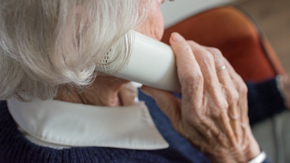 Eine Seniorin mit einem Telefonhörer am Ohr.&nbsp;