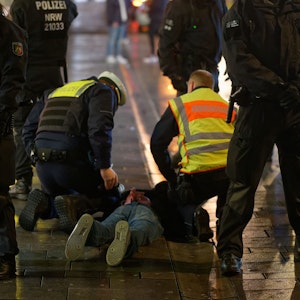Mitarbeiter des Ordnungsamtes und der Polizei halten in der Altstadt einen bei einer Kontrolle Geflüchteten auf dem Boden fest. +++ dpa-Bildfunk +++