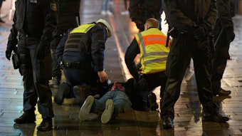 Mitarbeiter des Ordnungsamtes und der Polizei halten in der Altstadt einen bei einer Kontrolle Geflüchteten auf dem Boden fest.