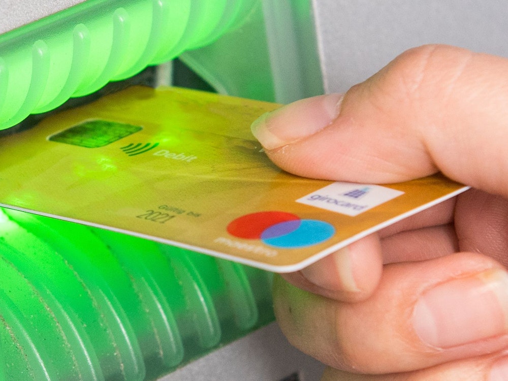 Kunden der Direktbanken ING und 1822direkt müssen ab 2022 Gebühren für ihre Girocard bezahlen. Das Foto zeigt eine Frau, die ihre Girocard in einen Geldautomaten schiebt.