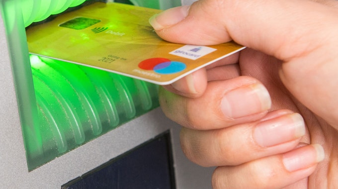 Kunden der Direktbanken ING und 1822direkt müssen ab 2022 Gebühren für ihre Girocard bezahlen. Das Foto zeigt eine Frau, die ihre Girocard in einen Geldautomaten schiebt.