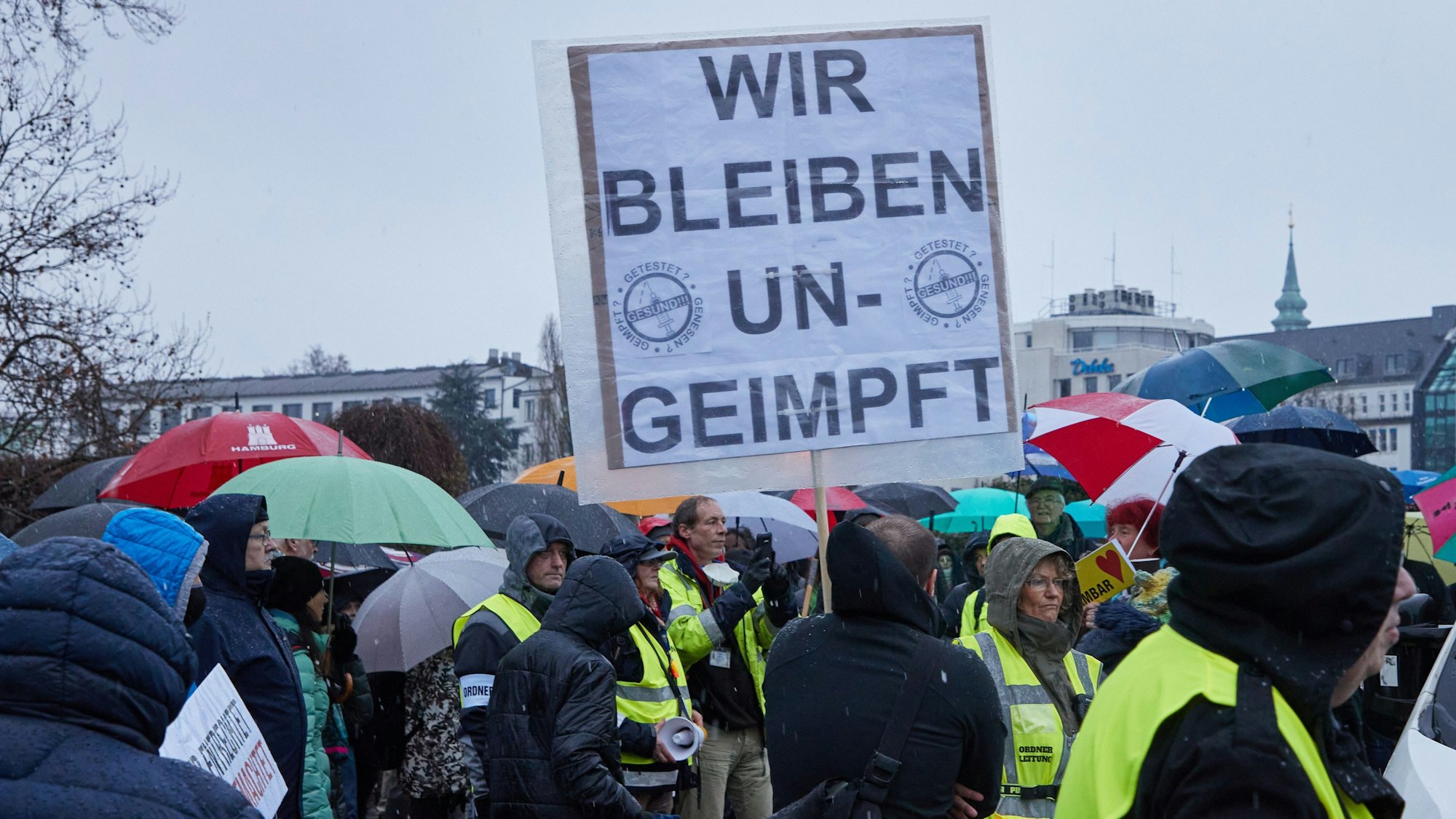 27.11.2021, Hamburg: Ein Teilnehmer einer Demonstration von Corona-Impfgegnern auf dem Glockengießerwall hält ein Transparent mit den Aufschrift "·Wir bleiben ungeimpft"·. Foto: Georg Wendt/dpa +++ dpa-Bildfunk +++
