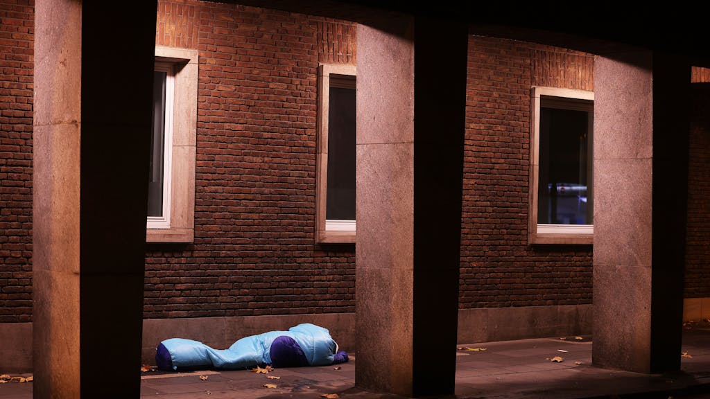 Ein Obdachloser liegt unter einer Überdachung in einer Passage.&nbsp;