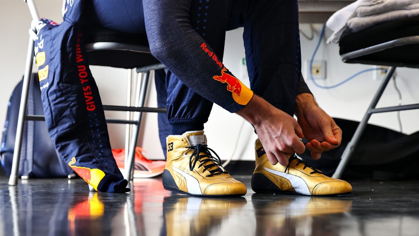Max Verstappen bindet sich seine goldenen Puma-Schuhe.