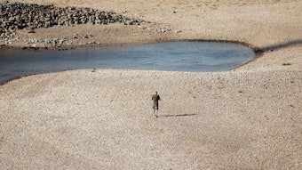 Ein Mann geht am 15. Oktober 2018 bei Niedrigwasser am Rhein entlang. Auch in diesem Jahr hatte der Rhein wieder extremes Niedrigwasser. Ereignisse wie dieses häufen sich in der Klimakrise.
