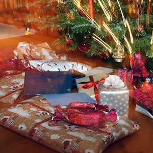 Verpackte Weihnachtsgeschenke liegen unter einem Christbaum.