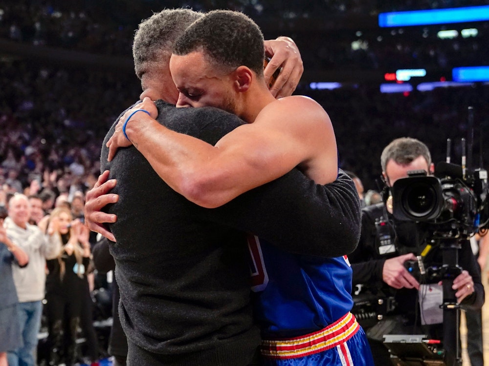Stephen Curry umarmt seinen Vater Dell Curry am Rand des Spielfelds.