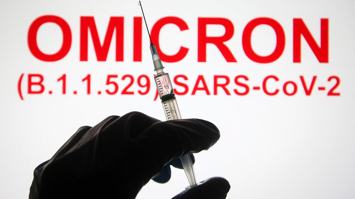 Eine Hand hält vor der Aufschrift „Omicron (B.1.1.529): SARS-CoV-2“ eine Spritze hoch.&nbsp;