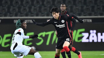 Manu Kone (l.) von Borussia Mönchengladbach versucht gegen Daichi Kamada (r.) von Eintracht Frankfurt an den Ball zu kommen, am 15. Dezember 2021.