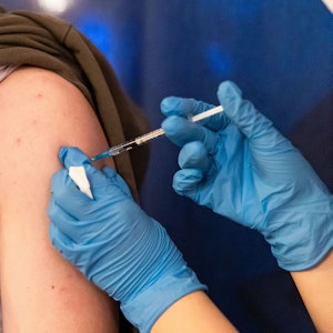 Einer Person wird der Corona-Impfstoff in den Oberarm verabreicht.