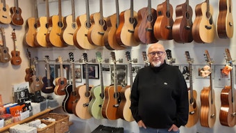 Uli Kurtinat steht vor einer Wand voller Gitarren in seinem Laden.