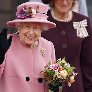Die britische Königin Elizabeth II. hält einen Blumenstrauß in der Hand und winkt, nachdem sie nach der Eröffnungszeremonie des walisischen Parlaments das Parlamentsgebäude verlässt.