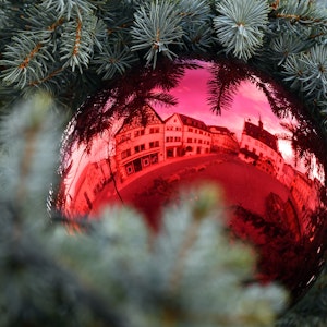 Eine rote Christbaumkugel hängt an einem Weihnachtsbaum.