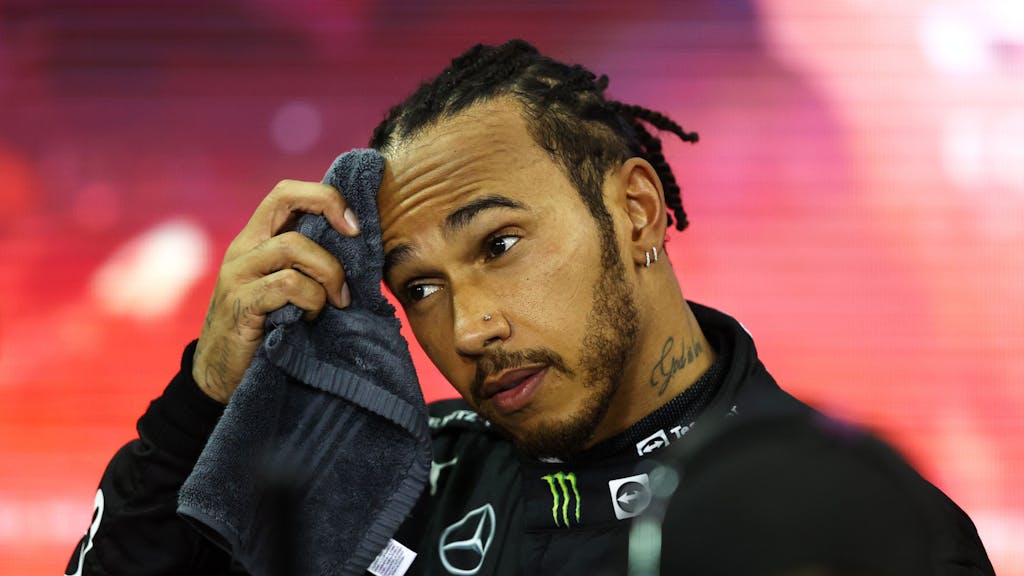 Lewis Hamilton wischt sich den Schweiß von der Stirn.