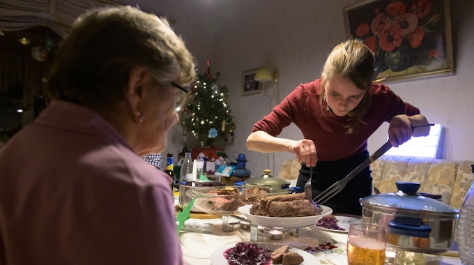 Nach einer vierzehntägigen, freiwilligen Selbstisolation feiert eine junge Frau mit ihren Großeltern an Heiligabend und serviert ihnen das Essen.&nbsp;