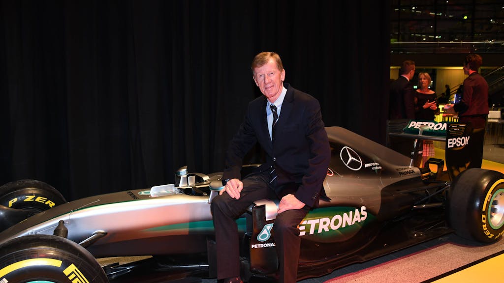 Walter Röhrl sitzt auf eine Formel-1-Auto von Mercedes.