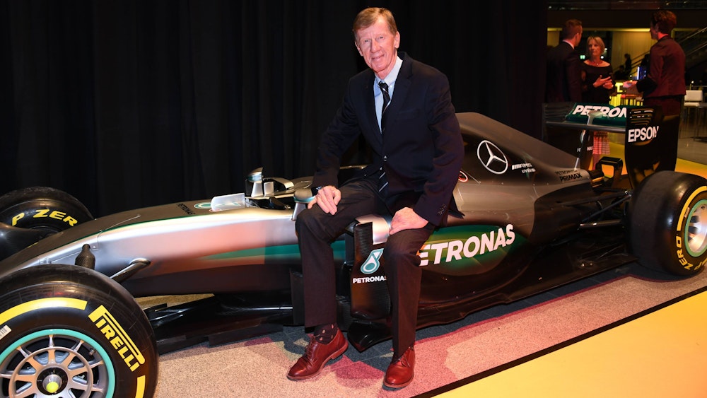 Walter Röhrl sitzt auf eine Formel-1-Auto von Mercedes.