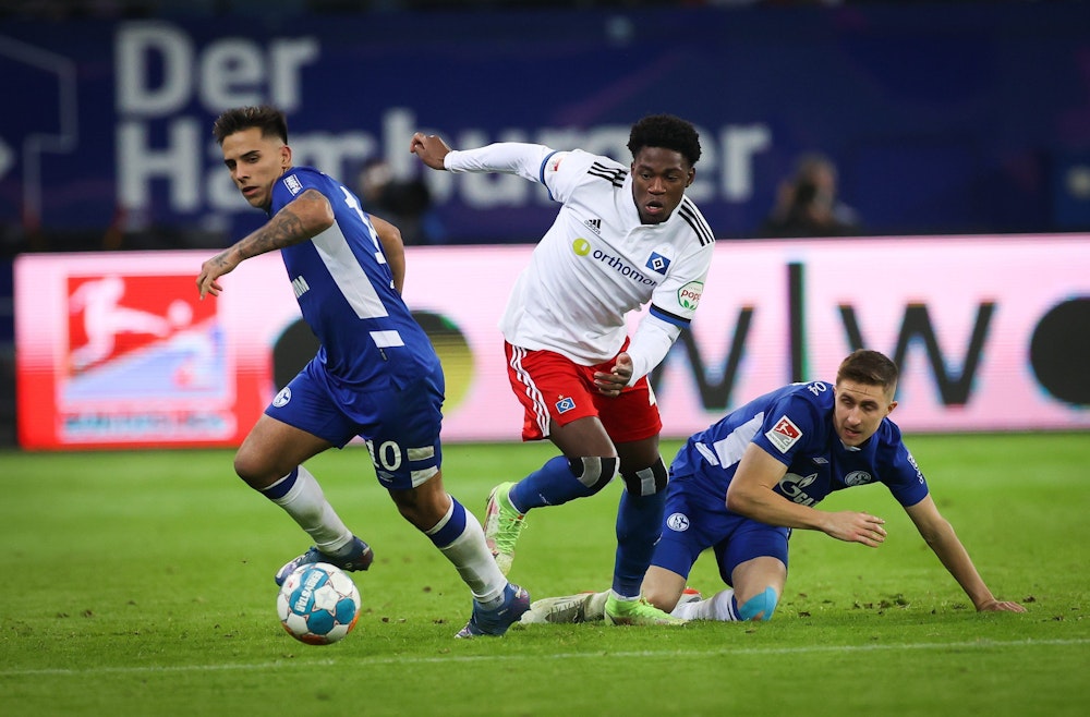 Hamburgs Faride Alidou (M) und Schalkes Rodrigo Zalazar (l) und Schalkes Thomas Ouwejan im Kampf um den Ball.