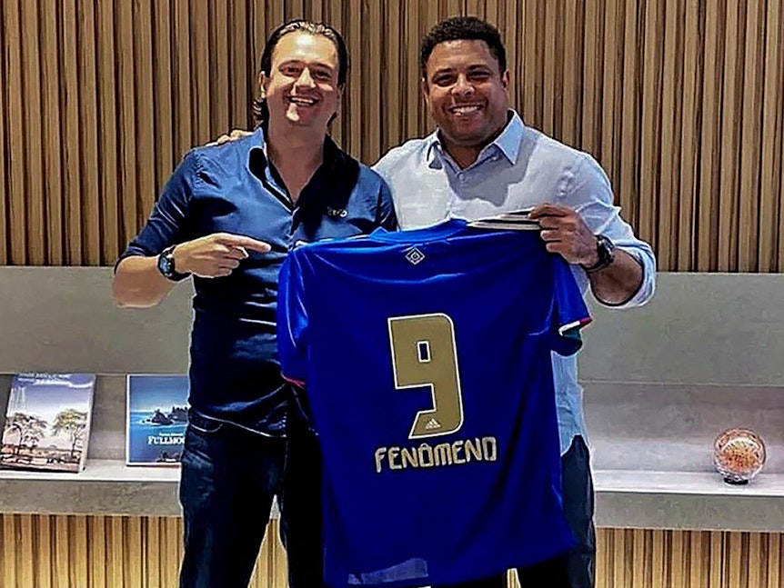 Sergio Santos Rodrigues und Ronaldo Nazario halten ein blaues Trikot mit der Rückennummer 9 und dem Namen „Fenomeno“, Ronaldos Spitznamen.