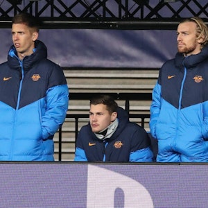 Dani Olmo, Josep Martinez und Emil Forsberg gucken in Trainingsjacken bekleidet auf das Spielfeld.