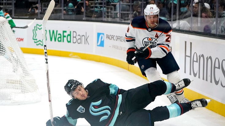 Seattle Kraken's Alex Wennberg, left, skids across the ice in front of Edmonton Oilers' Leon Draisaitl in the first period of an NHL hockey game Saturday, Dec. 18, 2021, in Seattle. (AP Photo/Elaine Thompson)