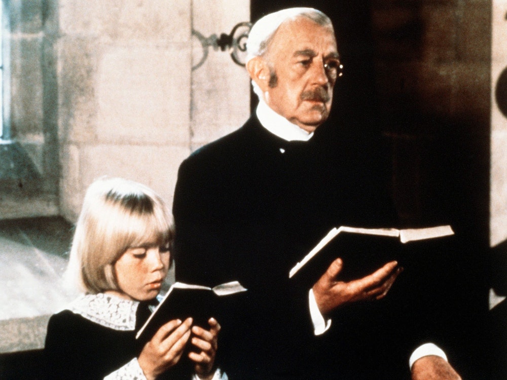 Der alte Earl of Dorincourt (Alec Guinness) steht neben seinem Enkel Ceddie (Ricky Schroder). Beide halten ein Gesangsbuch in der Hand.