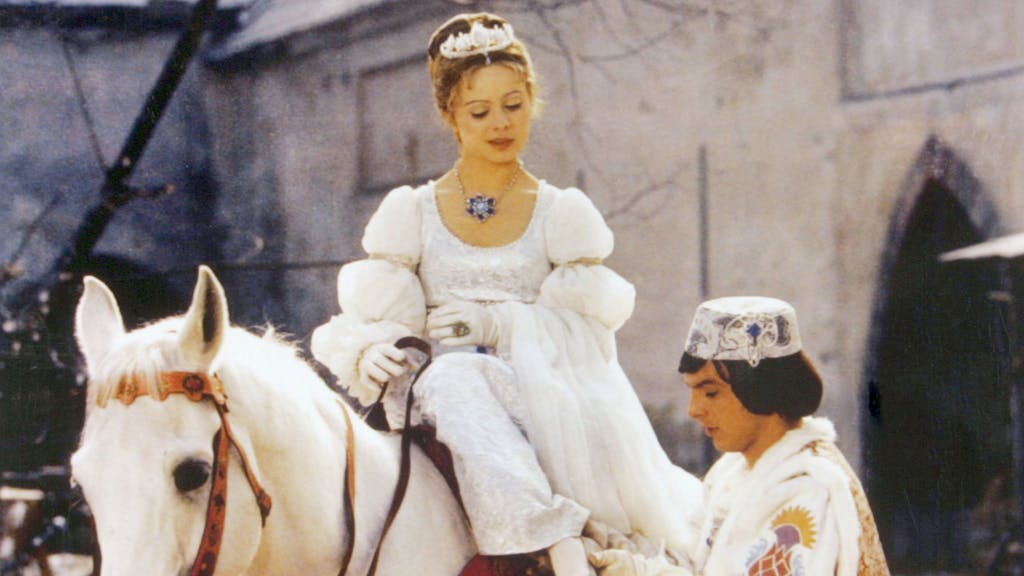 Der Prinz (Pavel Trávnícek) passt Aschenbrödel (Libuse Safránková) den verlorenen Schuh an in einer Szene aus „Drei Haselnüsse für Aschenbrödel“ .&nbsp;