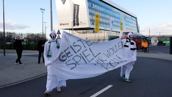 Als Geister verkleidete Gladbach-Fans halten am 11. März 2021 auf dem Gelände im Borussia-Park ein Transparent mit der Aufschrift: "Geisterspiel - Wir wollen rein" hoch.