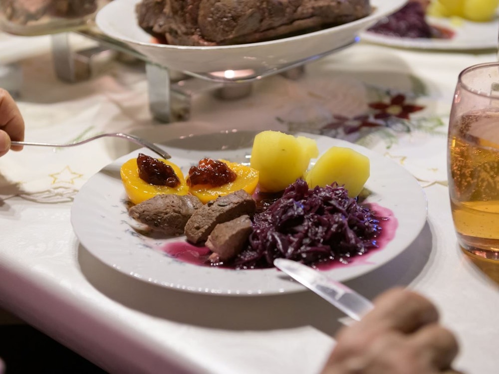 Hamburg: Damhirsch-Rücken mit Kartoffeln und Rotkohl sowie Preiselbeergelee auf Aprikosen liegen verzehrfertig auf einem Teller an Heiligabend.