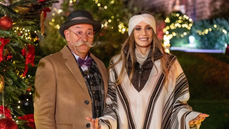 Horst Lichter und Cathy Hummels stehen bei der Weihnachtsaugabe „Bares für Rares XXL“ vor einem Weihnachtsbaum.
