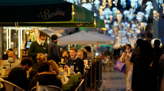 Menschen sitzen am 22. Dezember auf der Terrasse eines Cafés im weihnachtlich geschmückten Lissabonner Stadtteil Chiado. Nicht nur Portugal, auch Spanien und die USA werden Corona-Hochrisikogebiete.