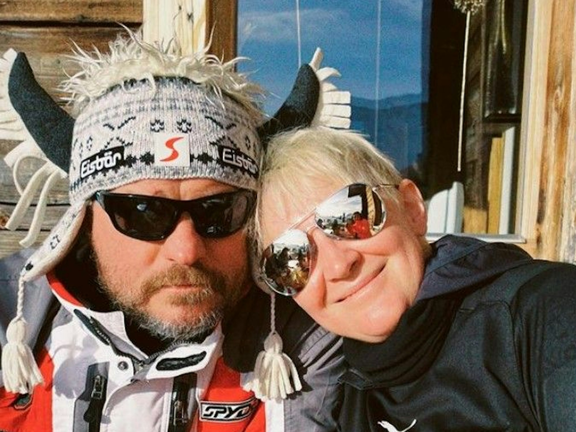 Steffen Baumgart sitzt mit seiner Frau Katja, Sonnenbrille und Hörner-Mütze an einer Skihütte in Österreich.
