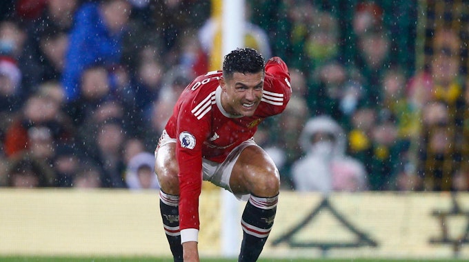 Cristiano Ronaldo hat ein schmerzverzerrtes Gesicht, geht in die Hocke und hält sich den Rücken.