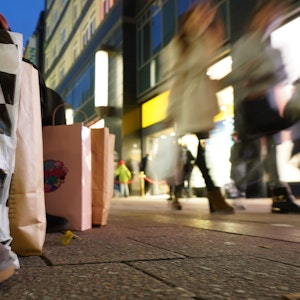 Eine Passantin sitzt mit ihren Einkaufstüten auf einer Sitzbank in der Innenstadt.
