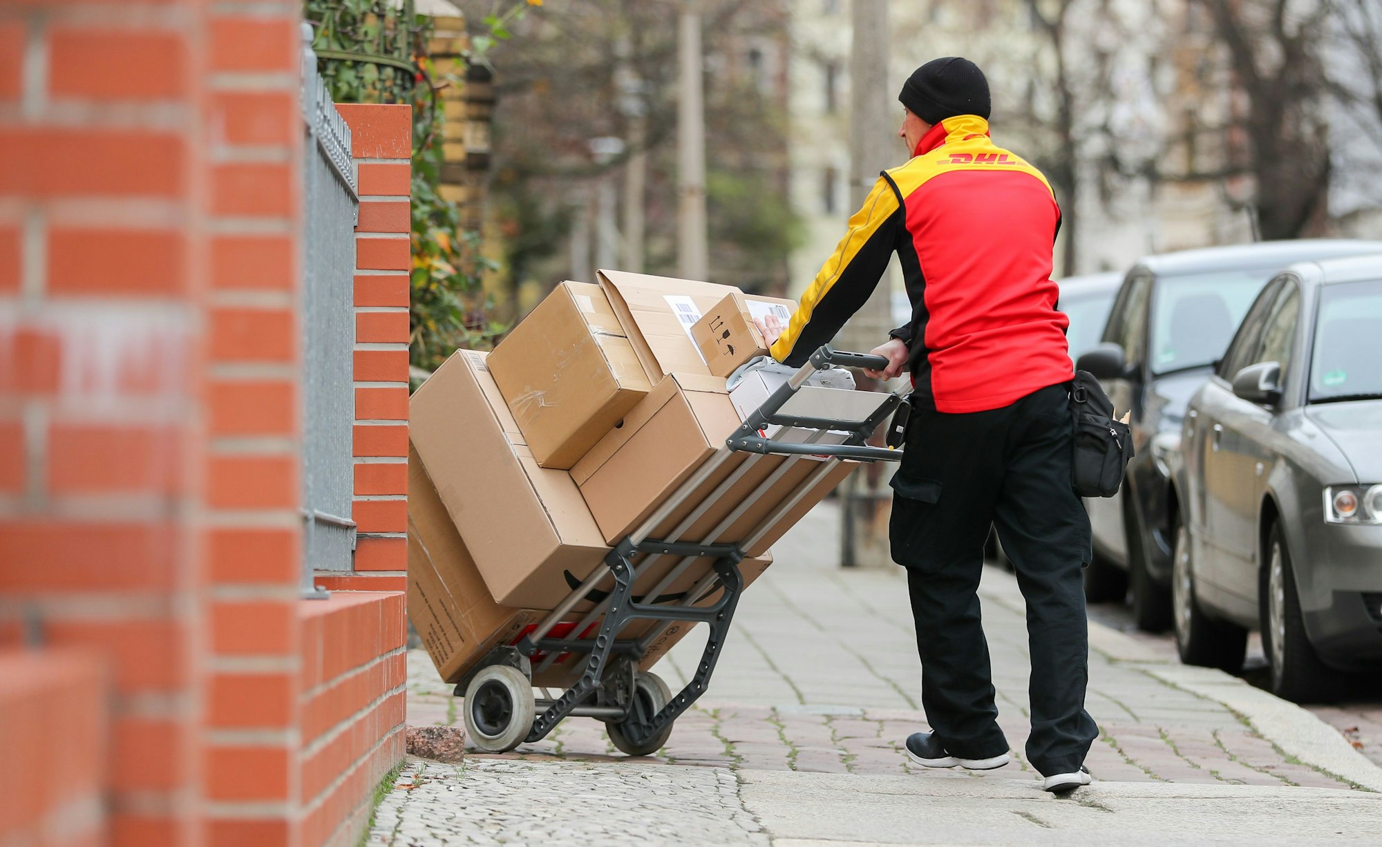 Ein DHL-Paketzusteller geht mit einer Sackkarre voll Pakete zu einem Haus im Paulusviertel. Das Bild wurde am 11. Dezember 2019 aufgenommen.