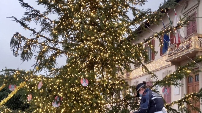 Ein Polizist entfernt am 28. Dezember 2021 „Hitler-Baumschmuck“ vom Gemeinde-Weihnachtsbaum vor dem Rathaus. Unbekannte hatten rund ein Dutzend rote Papp-Kreise mit Nazi-Abbildungen und dem Gesicht von Adolf Hitler an den Baum gehängt.