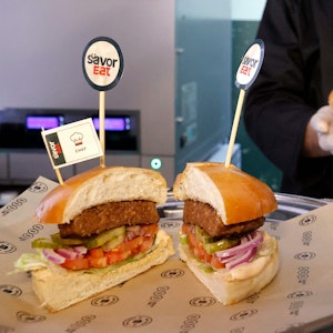 Ein Mitarbeiter präsentiert fertige Roboter-Burger.