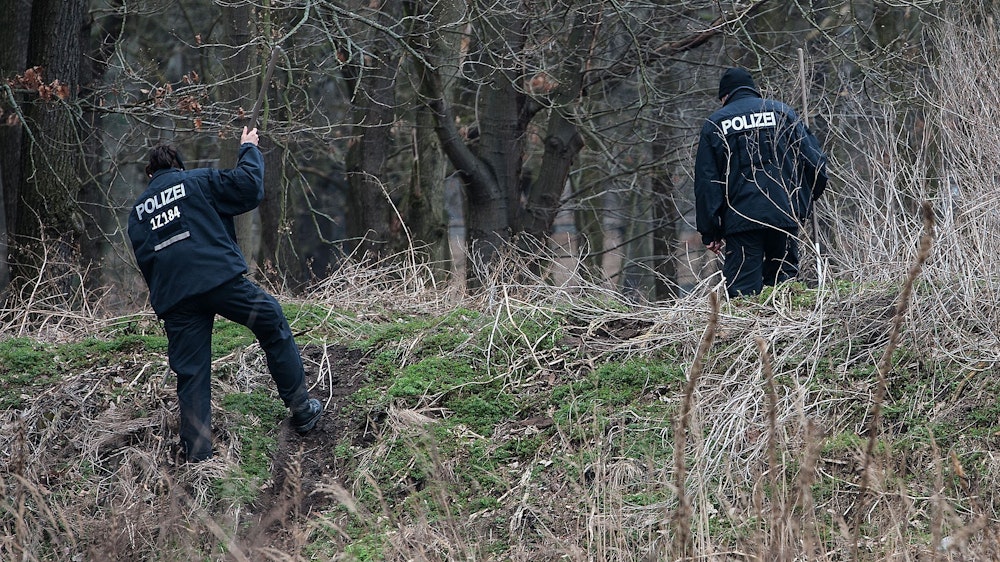 Zwei Polizisten suchen am 19.02.2014 in Berlin einen Grünbereich im Jungfernheidepark in Berlin-Charlottenburg ab.