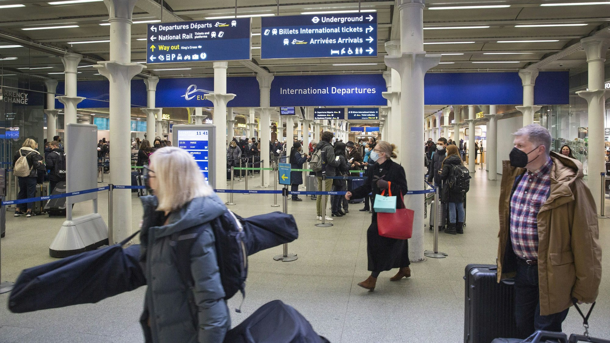 Menschen reisen vom Bahnhof London St Pancras nach Frankreich und laufen mit ihren Koffern umher.